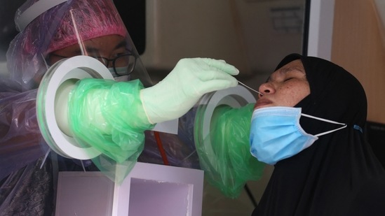 A hospital worker administers a swab test for Covid-19 coronavirus to a vendor from a fresh food market as part of efforts to allow the reopening of the market for the Eid al-Fitr festival marking the end of the Islamic holy month of Ramadan in southern Thailand's Pattani. (AFP)