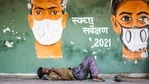 A man rests on a footpath under a Covid-19 coronavirus awareness painting in New Delhi on May 11, 2021.(AFP) A man rests on a footpath under a Covid-19 coronavirus awareness painting in New Delhi on May 11, 2021.(AFP)