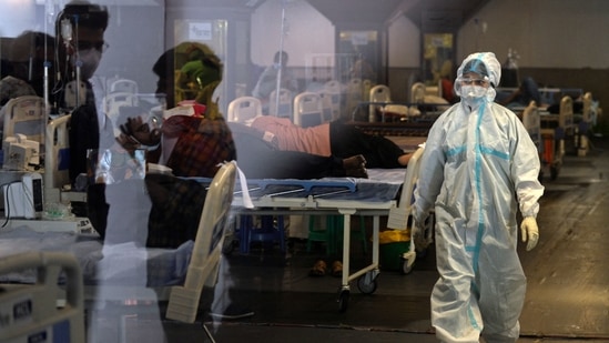 A health worker walks past Covid-19 patients inside a banquet hall temporarily converted into a Covid care centre in New Delhi on May 10. Delhi chief minister Arvind Kejriwal on May 10 said the national capital is preparing for the third wave of Covid-19 by augmenting infrastructure to a level where the city will be able to handle as many as 30,000 daily cases.(Arun Sankar / AFP)
