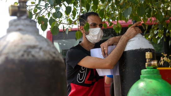 A relative of Covid-19 infected patients waiting with empty oxygen cylinders at a DTC bus depot to get them refilled under a Delhi government initiation, at Dwarka in New Delhi on May 10. Experts pointed out that the current wave of the infections has shown that besides Covid care centres for patients with moderate symptoms, the city will need more beds with oxygen and critical care support both in hospitals as well as the informal setups.(ANI)
