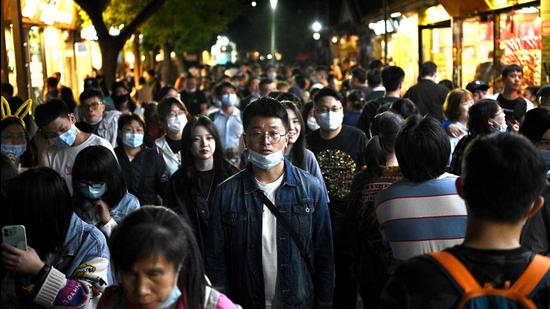 People walk through Nanluoguxiang alley during the Labour Day holidays, which took place from May 1 to 5, in Beijing on May 3, 2021. (AFP) People walk through Nanluoguxiang alley during the Labour Day holidays, which took place from May 1 to 5, in Beijing on May 3, 2021. (AFP)