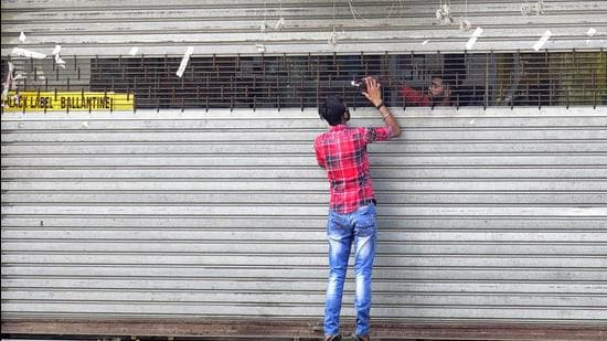 A vendor selling liquor from a partially drawn shutter in Ludhiana on Wednesday. (Gurpreet Singh/HT) A vendor selling liquor from a partially drawn shutter in Ludhiana on Wednesday. (Gurpreet Singh/HT)