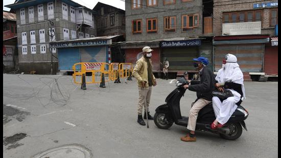 A cop stops two commuters during the lockdown in Srinagar on Wednesday. (Waseem Andrabi/HT) A cop stops two commuters during the lockdown in Srinagar on Wednesday. (Waseem Andrabi/HT)