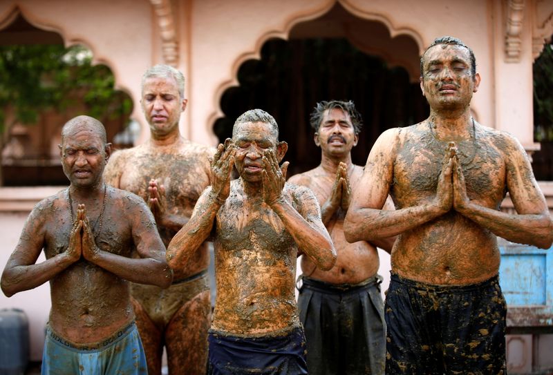 People pray after applying cow dung on their bodies during "cow dung therapy", believing it will boost their immunity to defend against the coronavirus disease (Covid-19) at the Shree Swaminarayan Gurukul Vishwavidya Pratishthanam Gaushala or cow shelter on the outskirts of Ahmedabad, India.