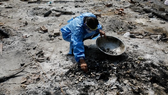 Anil Kumar Chawla, a relative of Rishi Raj Arora, who died from the coronavirus disease (Covid-19), collects ashes on the spot where he was cremated, as part of a ritual at a crematorium in New Delhi, India, April 30, 2021. (Reuters)