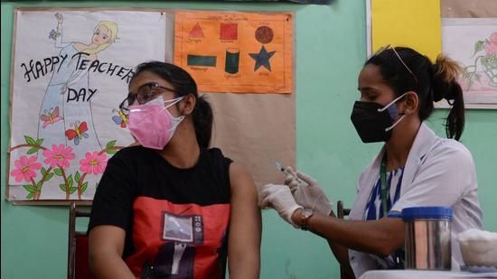 A health worker inoculates a young woman with a dose of Covishield vaccine at a school used as a vaccination centre in New Delhi on May 11. (AFP)