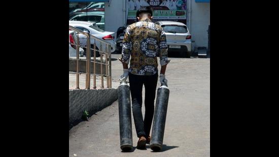 A health worker carries oxygen cylinders outside the Covid facility amid the rise in cases, in Jammu on Friday. (ANI) A health worker carries oxygen cylinders outside the Covid facility amid the rise in cases, in Jammu on Friday. (ANI)