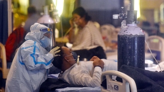 A healthcare worker in PPE coveralls tends to a Covid-19 patient at Shehnai Banquet Hall Covid care centre attached to LNJP Hospital, in New Delhi on May 14. Delhi’s test positivity rate too fell to 12.4%, the lowest since April 11, suggesting that the outbreak is receding after a punishing surge that began in mid-April and abated only in recent days.(Amal KS / HT Photo)