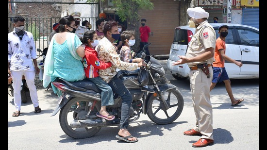 Police stopping a family of four at Basti Jodhewal Chowk in Ludhiana for violating the Covid protocol according to which not more than one person is allowed to travel on a two-wheeler. (Harsimar Pal Singh/HT) Police stopping a family of four at Basti Jodhewal Chowk in Ludhiana for violating the Covid protocol according to which not more than one person is allowed to travel on a two-wheeler. (Harsimar Pal Singh/HT)