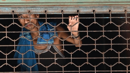 A worker looks out a closed shop during a lockdown imposed by the government amidst rising Covid-19 coronavirus cases, in New Delhi on May 16, 2021. (AFP)