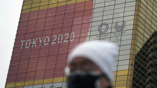 A man wearing a protective mask to help curb the spread of the coronavirus walks near a banner of the Tokyo 2020 Olympics and Paralympics.(AP) A man wearing a protective mask to help curb the spread of the coronavirus walks near a banner of the Tokyo 2020 Olympics and Paralympics.(AP)
