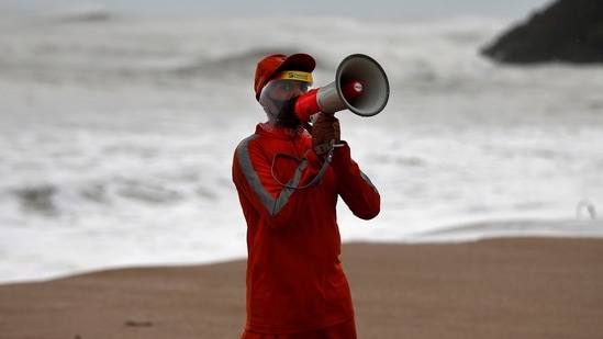 A member of the National Disaster Response Force (NDRF) uses a megaphone to appeal to fishermen to stay away from the shore ahead of Cyclone Tauktae in Veraval, Gujarat. (Reuters Photo)