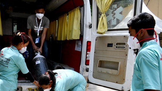 Health workers shift oxygen cylinders from an ambulance outside a temporarily converted isolation ward for Covid-19 patients in New Delhi. Health workers shift oxygen cylinders from an ambulance outside a temporarily converted isolation ward for Covid-19 patients in New Delhi.