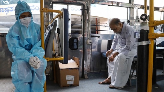 A health worker keeps a check on a Covid-19 patient receiving oxygen in a bus, in Bengaluru on May 15. Karnataka, which has recently emerged as the new Covid-19 hotspot, continues to remain the worst affected state at present with 6,00,168 active infections. Maharashtra follows with 4,70,595 active cases, HT reported.(PTI )