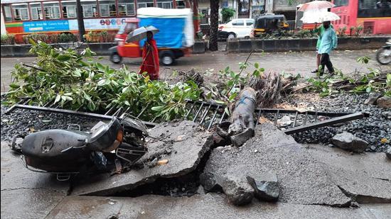 A two-wheeler was damaged when a tree fell on it due to the strong winds, in Thane on Monday, May 17. (Praful Gangurde/ HT photo)