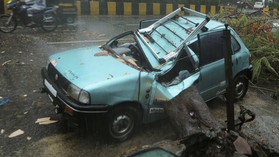 A damaged car is seen on a road after a tree fell on it due to strong winds caused by Cyclone Tauktae in Mumbai on May 17, 2021. (Reuters)