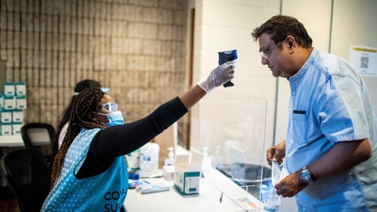A healthcare worker checks the temperature of a man at the Brampton civic centre in a pop-up clinic, in Ontario on Monday. (Reuters Photo)