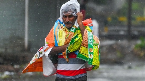 A man covers himself as he walks along a street in Amreli on May 18 after Cyclone Tautae hit the western coast of India. At least four people were counted dead in Gujarat, where Covid-19 vaccinations had been suspended for two days and authorities evacuated hundreds of thousands of people to temporary relief shelters.(Punit Paranjpe / AFP)