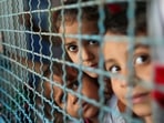 Palestinian children, who fled their homes due to Israeli air and artillery strikes, look through a window fence at a United Nations-run school where they take refuge, in Gaza City May 18, 2021. 