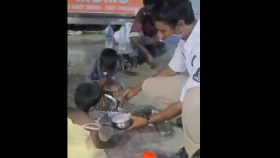 The image shows constable S Mahesh Kumar giving his lunchbox to the children.(Twitter@TelanganaCOPs) The image shows constable S Mahesh Kumar giving his lunchbox to the children.(Twitter@TelanganaCOPs)
