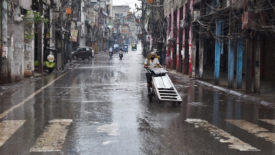 A worker pulls a handcart past closed shops while it rains during a lockdown imposed as a preventive measure against Covid-19, at Sadar Bazar in New Delhi on May 19. Before May 19, the lowest maximum temperature recorded in the month was 24.8°C, logged on May 13, 1982. (Ajay Aggarwal / HT Photo)