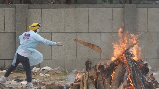 A volunteer adds wood to a funeral pyre of a Covid-19 victim at Seemapuri crematorium in New Delhi on May 18, 2021.(Amal KS / HT file photo) A volunteer adds wood to a funeral pyre of a Covid-19 victim at Seemapuri crematorium in New Delhi on May 18, 2021.(Amal KS / HT file photo)