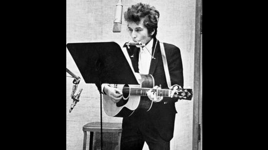 Playing harmonica and acoustic guitar while singing into a microphone, at Columbia's Studio A in New York City, in 1965. (Getty Images) Playing harmonica and acoustic guitar while singing into a microphone, at Columbia's Studio A in New York City, in 1965. (Getty Images)