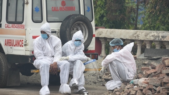 Health workers take a break from cremating the deceased, during the second wave of coronavirus, in New Delhi.(PTI)