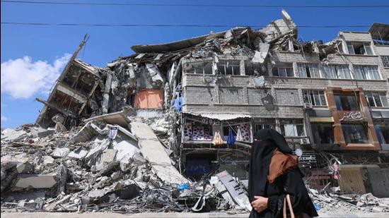 A Palestinian woman walks past a destroyed building in the Al-Rimal commercial district in the Gaza City on Saturday. (AFP)