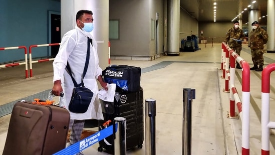 A passenger flying in from India arrives with his luggage at the Fiumicino International airport. (AFP)