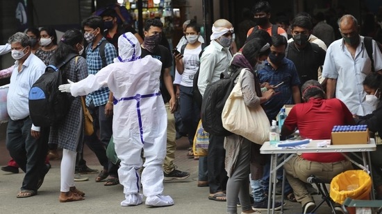 Karnataka, Maharashtra and Kerala witnessed a decline in their respective active caseload since Friday. In picture - Health worker directs arriving passengers towards Covid-19 testing counter outside a train station in Bengaluru.(AP)