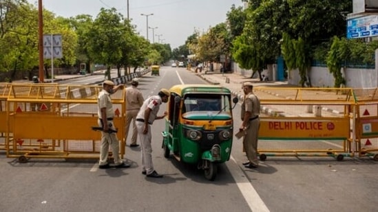 Delhi Police officers stop an autorickshaw at a check point during a weekend lockdown in New Delhi. (AP) Delhi Police officers stop an autorickshaw at a check point during a weekend lockdown in New Delhi. (AP)