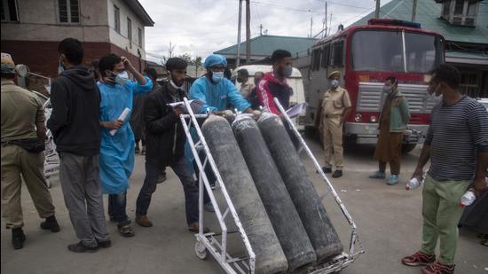 Local men hired by administration assist transport of oxygen cylinders on the premises of a hospital in Srinagar on Sunday. (AP) Local men hired by administration assist transport of oxygen cylinders on the premises of a hospital in Srinagar on Sunday. (AP)