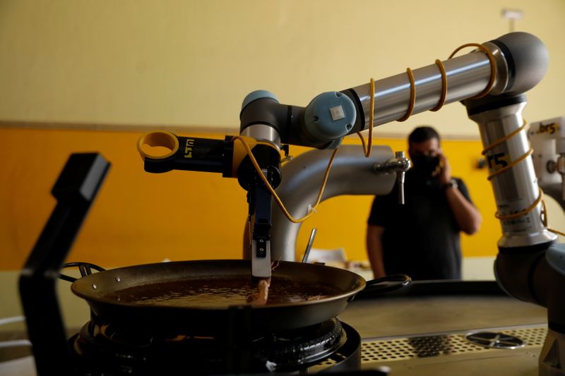 A robot created by Spanish companies br5 and Mimcook drops shrimp into a paella during a demonstration at a warehouse in San Fernando de Henares, outside Madrid, Spain. (REUTERS)