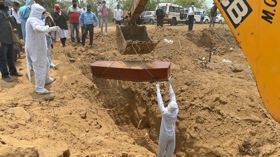 An employee of Michael Undertakers and Ambulance Services wearing PPE suit, lays a coffin to rest during the burial of a Covid-19 victim at a Christian cemetery in Pali village near Faridabad on May 8. According to the Union ministry of health and family welfare (MoHFW) dashboard on May 24 morning, India registered 4,454 Covid-19 related deaths in the last 24 hours, taking the death toll to 303,720. (Sajjad Hussain / AFP) An employee of Michael Undertakers and Ambulance Services wearing PPE suit, lays a coffin to rest during the burial of a Covid-19 victim at a Christian cemetery in Pali village near Faridabad on May 8. According to the Union ministry of health and family welfare (MoHFW) dashboard on May 24 morning, India registered 4,454 Covid-19 related deaths in the last 24 hours, taking the death toll to 303,720. (Sajjad Hussain / AFP)