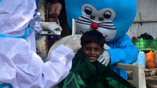 Dressed as Doremon, the cartoon character, social activist Ashok Kurmi gives a proper haircut to slum children, as barber shops are closed due to lockdown restrictions at Antop Hill, in Mumbai, India, on Monday, May 24, 2021. (Photo by Anshuman Poyrekar/Hindustan Times)