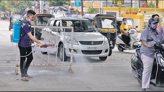 A PMC staffer sanitises the area around a barricade in Bibwewadi on Sunday. (Rahul Raut/HT PHOTO) A PMC staffer sanitises the area around a barricade in Bibwewadi on Sunday. (Rahul Raut/HT PHOTO)