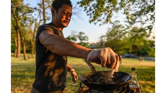 Chef Bun Lai seasons cicadas as he fries them at Fort Totten Park in Washington, DC on May 23. For those who answered the call, the culinary adventure began by collecting some of the tastiest-looking bugs. Stella Roque, a 36-year-old who grew up with a fear of insects, was not overly eager, but viewed it as a way to overcome her phobia. "I'm here today because Bun Lai invited me to try cooked cicadas, and I thought it was going to be an interesting experience," she told AFP.(Andrew Caballero-Reynolds / AFP)