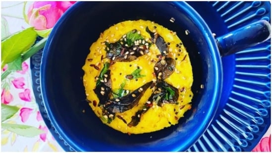 Dhokla: In a microwave-safe bowl add 1 cup besan, 1/3 teaspoon turmeric, 1/4 teaspoon asafoetida, 1 teaspoon ginger chilli paste, 1 teaspoon salt, 2 teaspoons powdered sugar, 1/2 curd, 1 tablespoon vegetable oil, and mix well. Add little by little water and keep mixing till it turns into a smooth batter. Then microwave it for 3 1/2 minutes. In a separate pan, add 1 tablespoon oil, mustard seeds, curry leaves and green chillies. Saute it for a few seconds and add 1/4 cup water. Add this mixture to the dhokla and let it sit in the refrigerator for 20 minutes.(Instagram/carbsmysoulmate)
