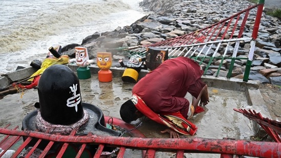A Hindu priest prays to Lord Jagannath at a seafront temple in Balasore, on May 26. Most parts of Odisha also received heavy rains. Umashankar Dash, a scientist at the Regional Meteorological Centre in Bhubaneswar, told PTI that the surge of 1.5-3.8 metre is likely in the area when the wind speed hits a peak during landfall. The reason behind such a high storm surge is also partially due to full-moon activity.(Dibyangshu Sarkar / AFP)