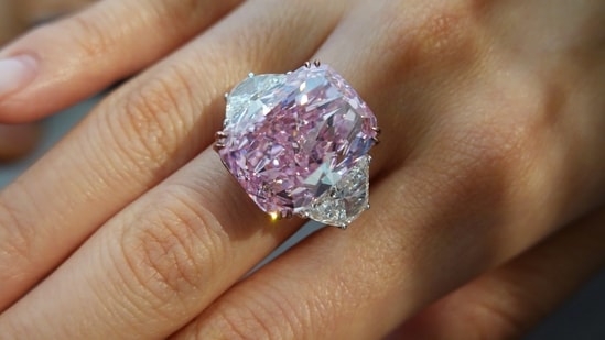An employee poses with a 15.81 carat fancy vivid purple pink diamond ring, which is called The Sakura Diamond, during a preview at Christie’s.(REUTERS)