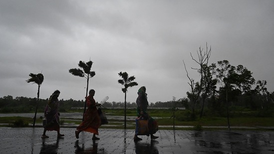 Locals residents walk to a shelter as Cyclone Yaas barrels towards the coast, in Digha on May 26. Odisha has moved 5.8 lakh people to safer places, while West Bengal has moved 15 lakh people ahead of the cyclone.(Dibyangshu Sarkar / AFP)