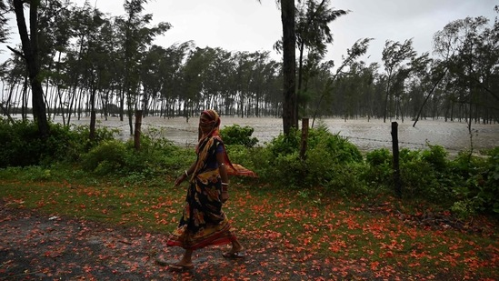 A woman walks past a flooded area in Digha on May 26. The maximum wind speed in Digha reached around 90 km per hour. It was 68 kmph at Fraserganj in South 24 Parganas, and in Kolkata, the highest wind speed was recorded at 62 kmph, HT reported.(Dibyangshu Sarkar / AFP)