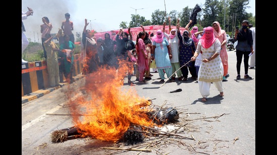 Farmers burning an effigy of PM Modi, Haryana CM Manhor Lal Khattar and deputy CM Dushyant Chautala during a protest at IMT Chowk, Khedi Saadh village in Rohtak on Wednesday. (Manoj Dhaka/HT)