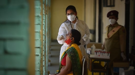 A health worker in PPE Coveralls collects a swab sample to test for Covid infection at a school in Janakpuri, New Delhi, India, on Wednesday, May 26, 2021. (Photo by Sanchit Khanna/ Hindustan Times)