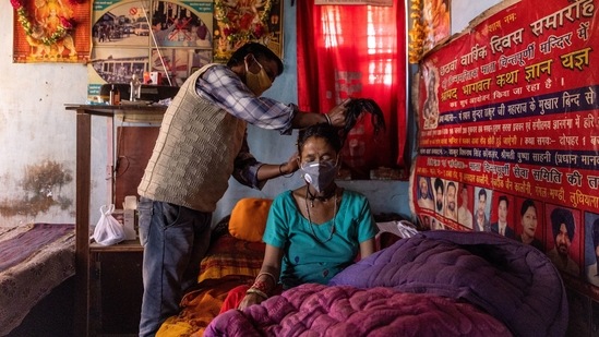 Suresh Kumar assists Pramila Devi before she was taken to a local government dispensary, at their home in Kaljikhal, on May 23. Two weeks after their eldest daughter's marriage Devi suffered a bout of diarrhoea.(Danish Siddiqui / REUTERS)