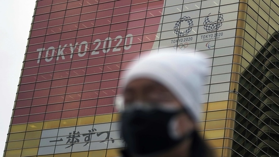 A man wearing a protective mask to help curb the spread of the coronavirus walks near a banner of the Tokyo 2020 Olympics and Paralympics.(AP) A man wearing a protective mask to help curb the spread of the coronavirus walks near a banner of the Tokyo 2020 Olympics and Paralympics.(AP)
