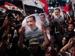 Syrian President Bashar Assad supporters hold up national flags and pictures of Assad as they celebrate at Omayyad Square, in Damascus.
