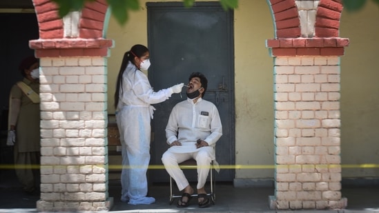 A health worker collects a swab sample from man to test for Covid-19 infection, at a school in Janakpuri, New Delhi, on May 26. Delhi’s Covid-19 graph continued its downward trajectory on May 27, with daily infections falling sharply. Delhi added 1,072 new cases of Covid-19, over 400 fewer than the previous day, HT reported.(Sanchit Khanna / HT Photo)