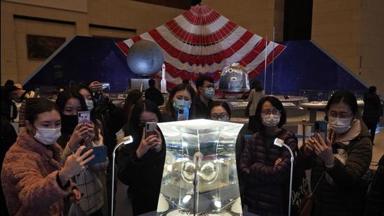 Visitors to the National Museum look at a display of the lunar rock samples retrieved from the moon by China's Chang'e 5 lunar lander late last year in Beijing on March 12, 2021. (AP) Visitors to the National Museum look at a display of the lunar rock samples retrieved from the moon by China's Chang'e 5 lunar lander late last year in Beijing on March 12, 2021. (AP)